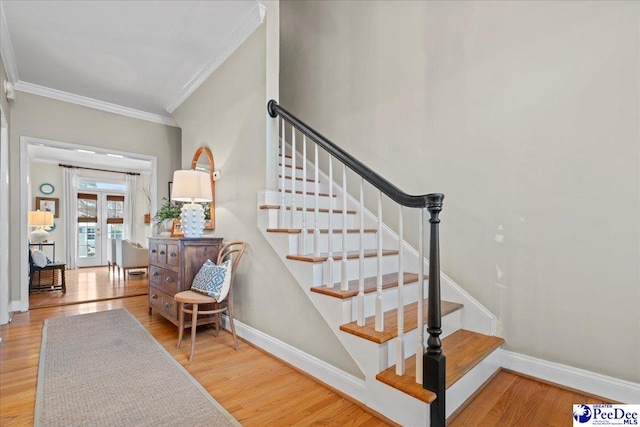 staircase featuring hardwood / wood-style floors, ornamental molding, and french doors