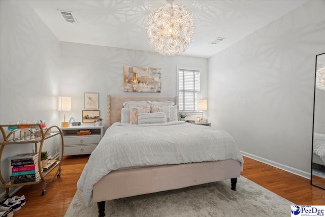 bedroom with wood-type flooring and a notable chandelier