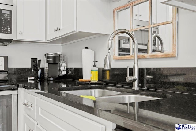 kitchen with white cabinetry, sink, dark stone counters, and stainless steel range with electric stovetop