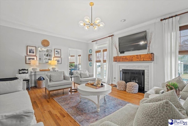 living room with an inviting chandelier, hardwood / wood-style flooring, a wealth of natural light, and ornamental molding