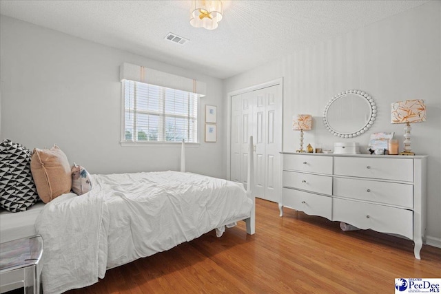 bedroom with a textured ceiling, a closet, and light wood-type flooring