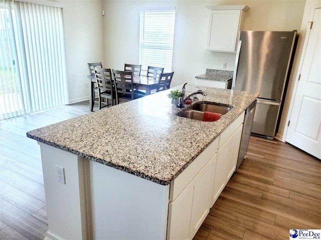 583 Polaris Way, Summerville, SC 29486 - kitchen featuring appliances with stainless steel finishes, a sink, wood finished floors, white cabinets, and light stone counters