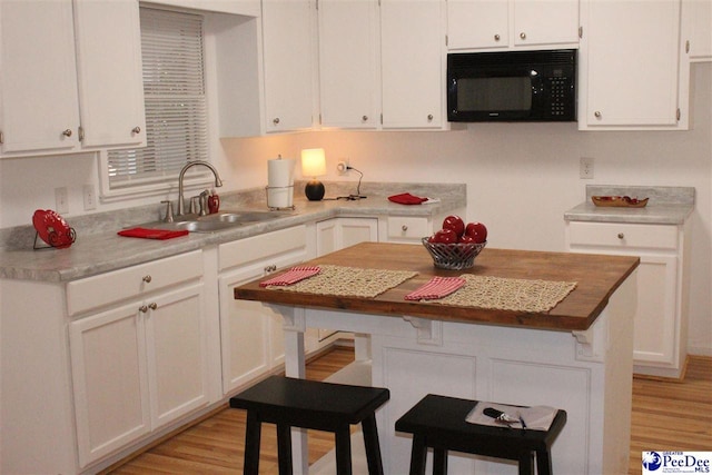 kitchen with sink, light hardwood / wood-style floors, and white cabinets