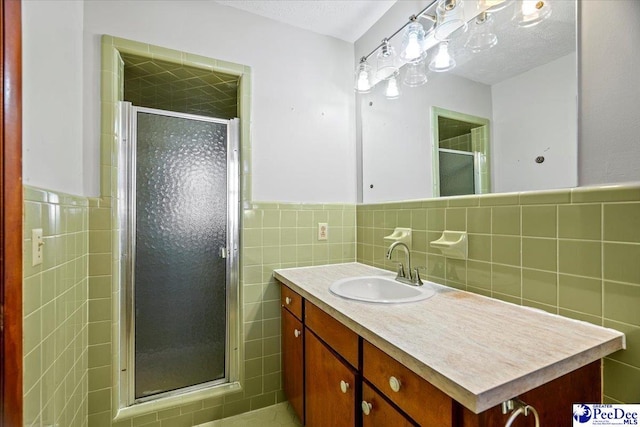 bathroom featuring tile walls, vanity, a textured ceiling, and an enclosed shower