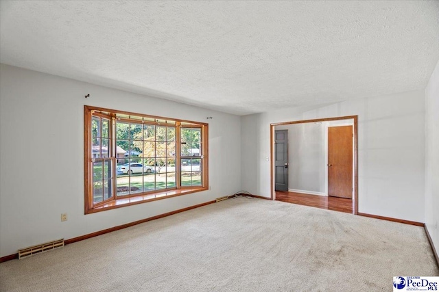 carpeted empty room with a textured ceiling