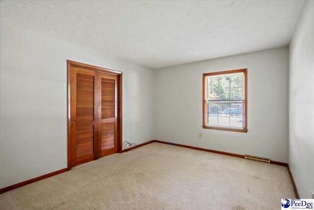 unfurnished bedroom with light colored carpet, a closet, and a textured ceiling