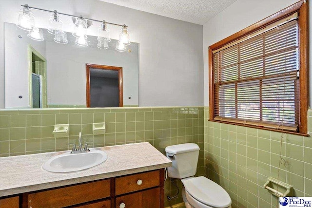 bathroom featuring vanity, tile walls, toilet, and a textured ceiling