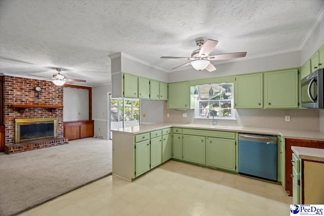 kitchen with sink, appliances with stainless steel finishes, kitchen peninsula, green cabinets, and a fireplace