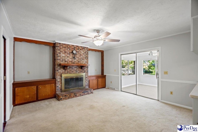 carpeted living room featuring crown molding, a textured ceiling, ceiling fan, and a fireplace