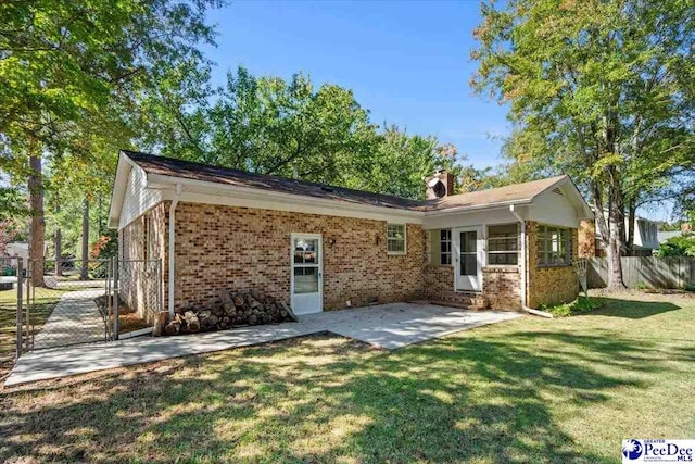 back of house with a patio area and a lawn