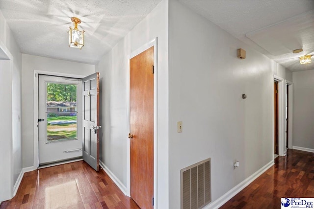 doorway to outside with dark hardwood / wood-style floors and a textured ceiling