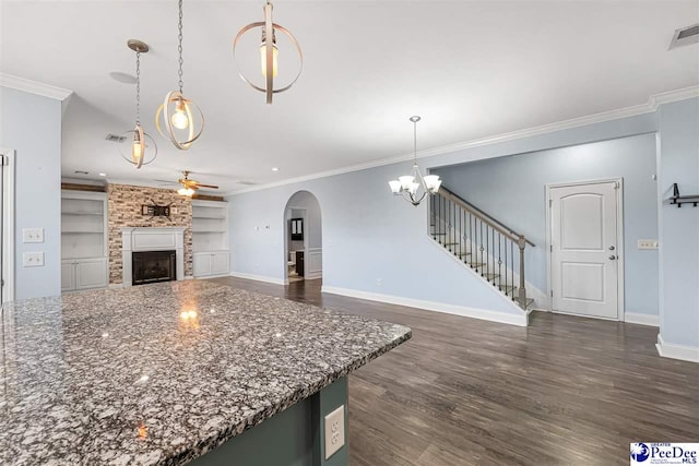 kitchen featuring built in shelves, crown molding, hanging light fixtures, a large fireplace, and ceiling fan