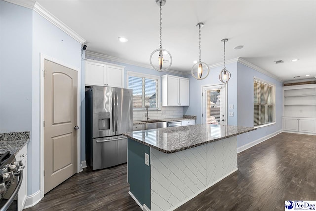 kitchen featuring stainless steel appliances, pendant lighting, dark stone countertops, and white cabinets