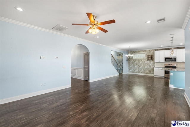 unfurnished living room with ceiling fan with notable chandelier, ornamental molding, and dark hardwood / wood-style floors