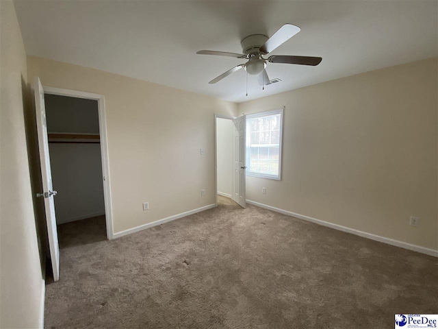 unfurnished bedroom featuring ceiling fan, carpet flooring, a closet, and a spacious closet