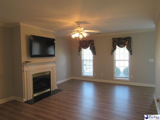 unfurnished living room with crown molding, dark wood-type flooring, a glass covered fireplace, a ceiling fan, and baseboards