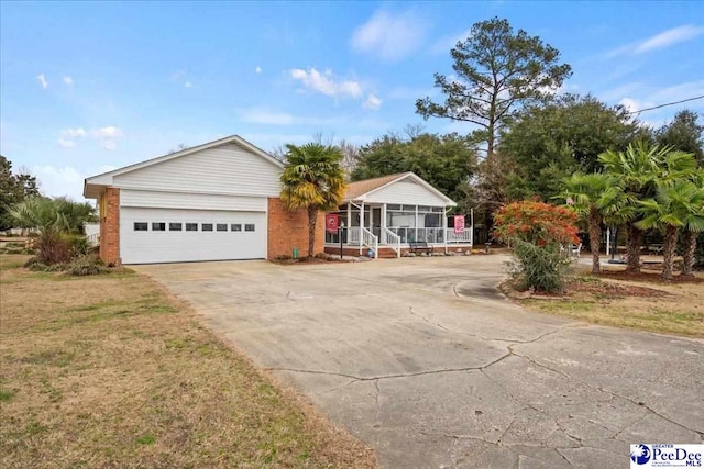 single story home featuring a garage, a sunroom, and a front yard