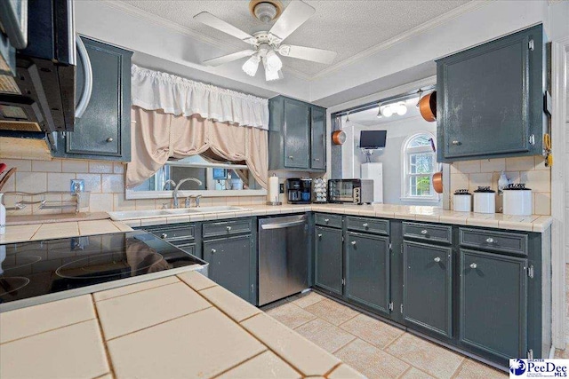 kitchen with stainless steel dishwasher, ornamental molding, and tile counters