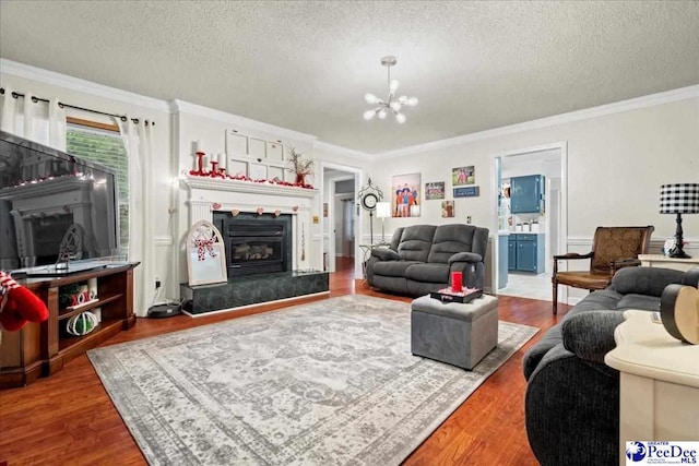 living room with a notable chandelier, wood-type flooring, a textured ceiling, and crown molding