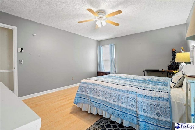 bedroom featuring ceiling fan, hardwood / wood-style floors, and a textured ceiling