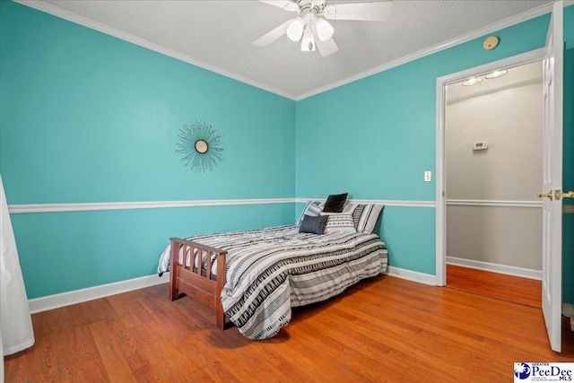 bedroom featuring crown molding, ceiling fan, wood-type flooring, and a textured ceiling