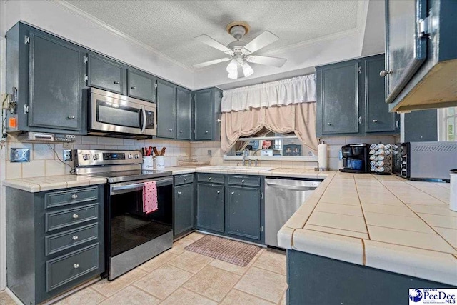 kitchen featuring tasteful backsplash, ornamental molding, appliances with stainless steel finishes, and sink