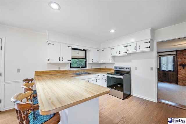 kitchen featuring sink, light hardwood / wood-style floors, white cabinets, stainless steel electric range oven, and kitchen peninsula