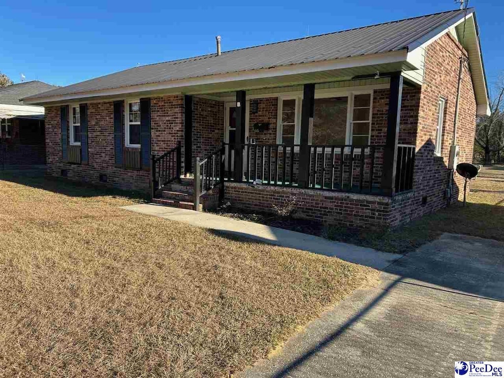 ranch-style home with covered porch and a front lawn