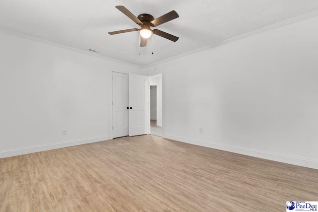 empty room featuring ornamental molding, baseboards, a textured ceiling, and light wood finished floors