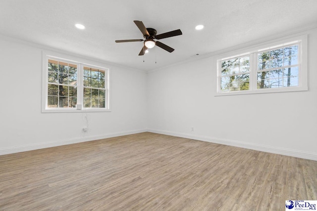 spare room featuring ornamental molding, light wood-type flooring, recessed lighting, and baseboards