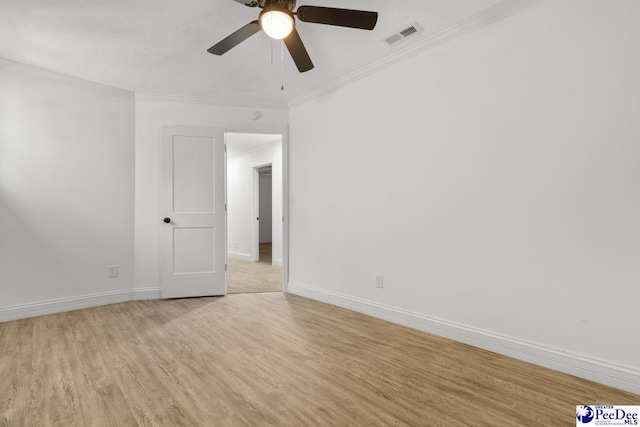 spare room featuring light wood-style flooring, visible vents, baseboards, and crown molding