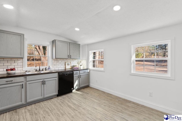 kitchen featuring gray cabinets, dark countertops, black dishwasher, and a sink