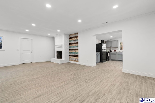 unfurnished living room with baseboards, light wood-type flooring, a fireplace, and recessed lighting