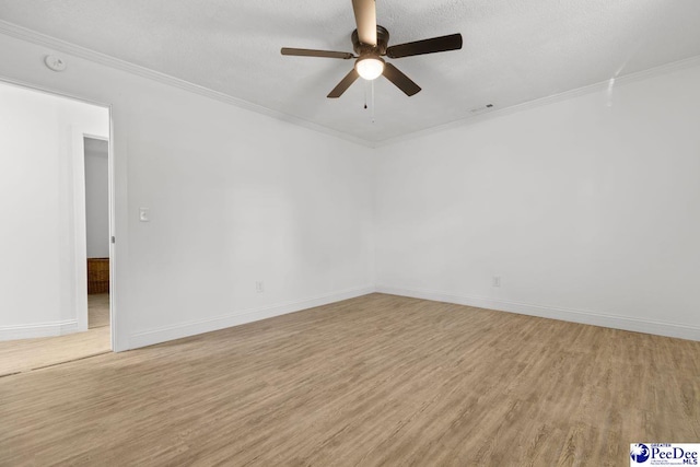 spare room with ornamental molding, light wood finished floors, a textured ceiling, and baseboards