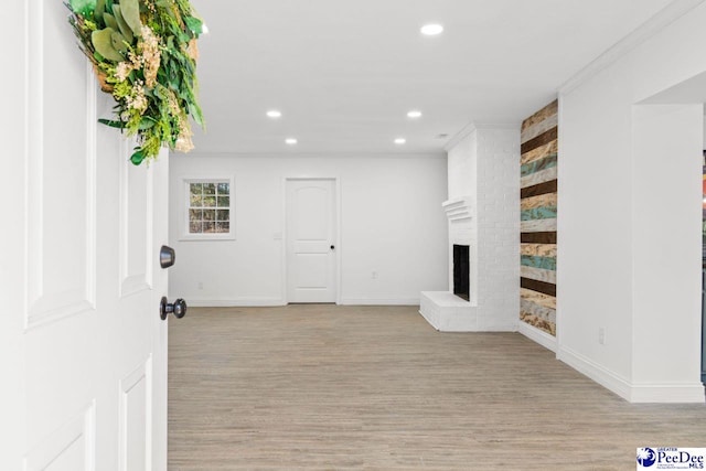 interior space with baseboards, crown molding, light wood-style floors, a fireplace, and recessed lighting