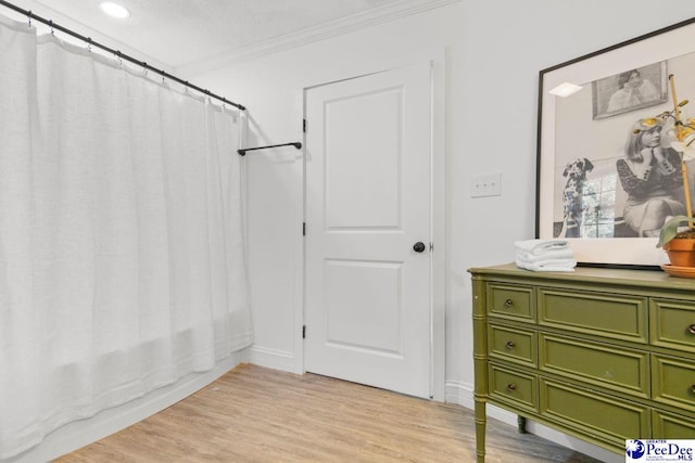 bathroom with crown molding, shower / bathtub combination with curtain, and wood finished floors