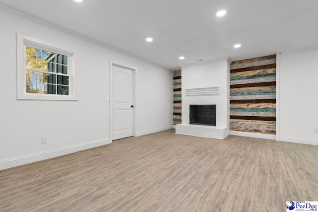 unfurnished living room with recessed lighting, light wood-style flooring, ornamental molding, a brick fireplace, and baseboards