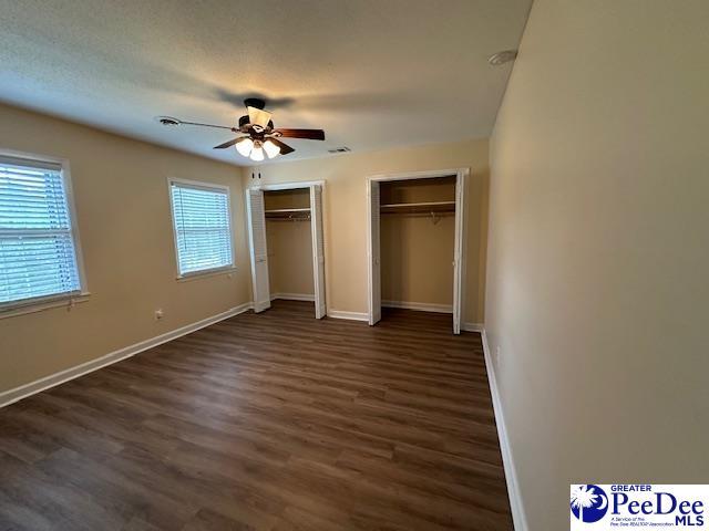 1328 Salem Rd, Hartsville, SC 29550 - unfurnished bedroom with multiple closets, dark wood finished floors, baseboards, and a ceiling fan
