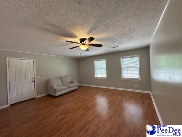 1328 Salem Rd, Hartsville, SC 29550 - unfurnished living room with a textured ceiling, wood finished floors, a ceiling fan, and baseboards