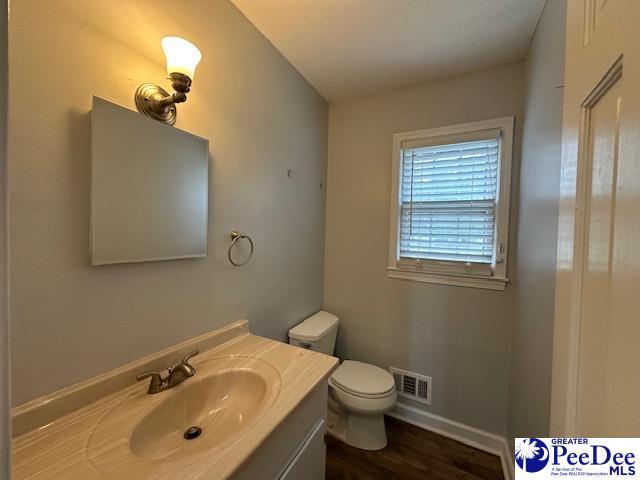 1328 Salem Rd, Hartsville, SC 29550 - half bathroom featuring toilet, vanity, wood finished floors, and baseboards