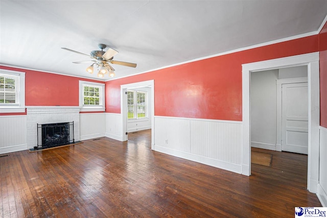 1461 King Ave, Florence, SC 29501 - unfurnished living room featuring ceiling fan, wainscoting, wood-type flooring, a brick fireplace, and crown molding