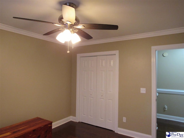 unfurnished bedroom featuring a closet, crown molding, baseboards, and dark wood-style flooring