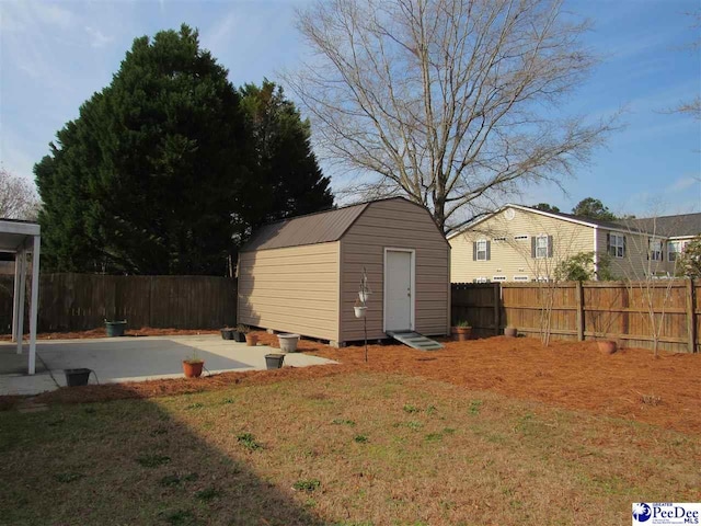 view of yard featuring an outdoor structure, a storage shed, a fenced backyard, and a patio area