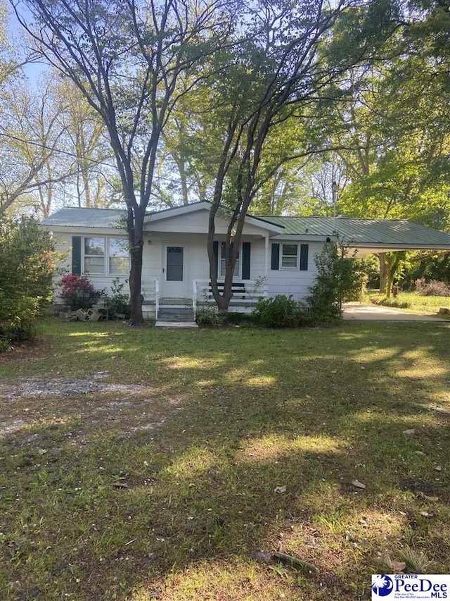 ranch-style home with metal roof, an attached carport, and a front lawn
