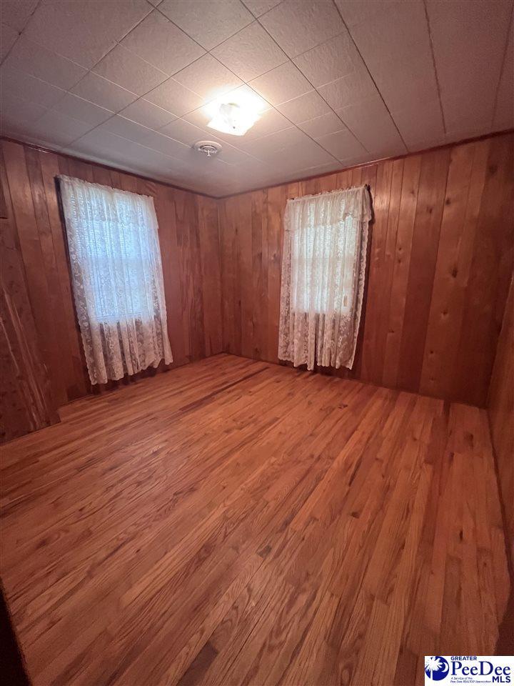 unfurnished room with wooden walls and wood finished floors