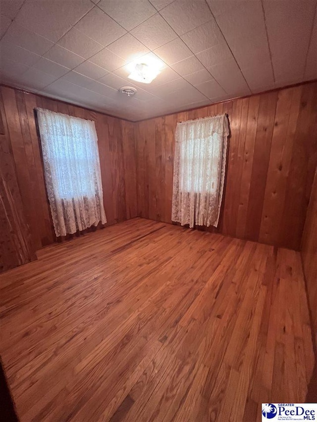 unfurnished room with wooden walls and wood finished floors