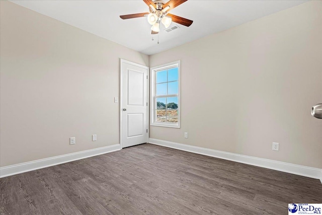 spare room featuring dark wood-style flooring, visible vents, ceiling fan, and baseboards