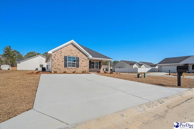 ranch-style house featuring concrete driveway, brick siding, fence, and central AC unit