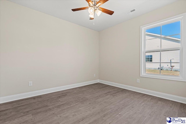 unfurnished room with baseboards, visible vents, ceiling fan, and dark wood-type flooring