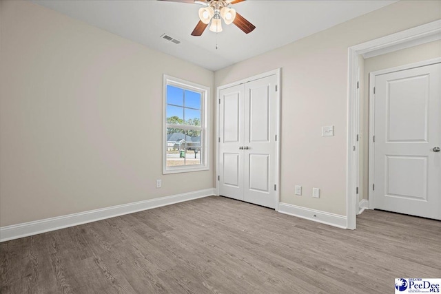 unfurnished bedroom featuring a closet, visible vents, baseboards, and wood finished floors